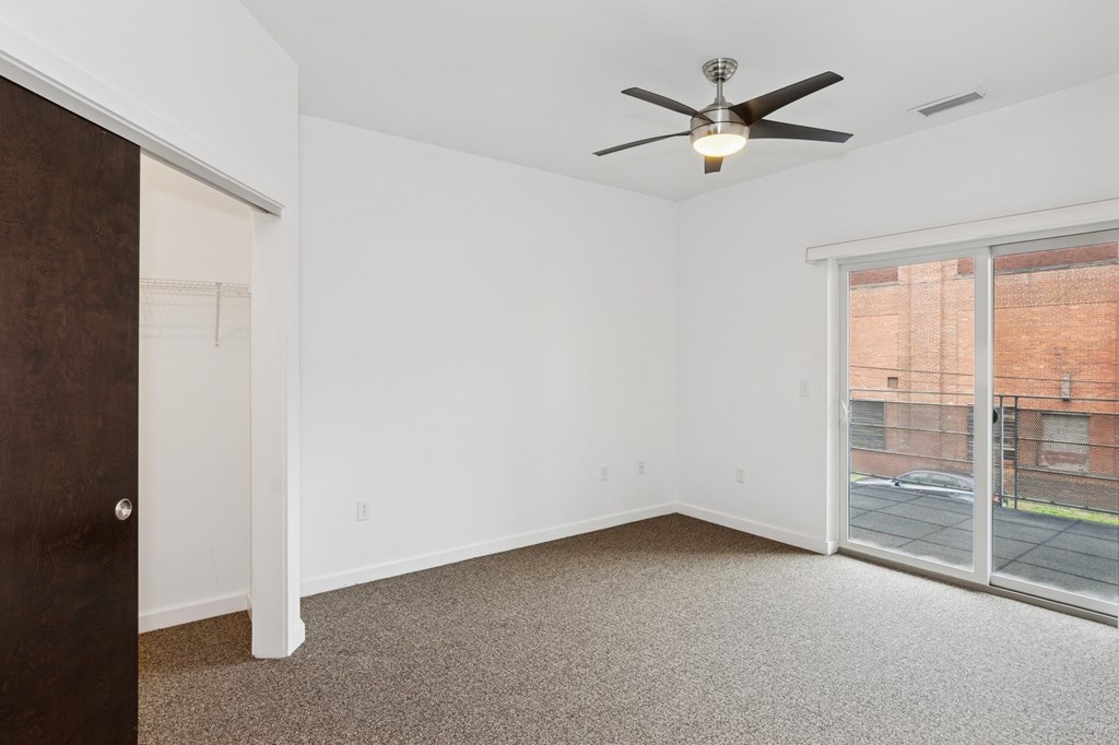 A room with a ceiling fan and a sliding glass door.