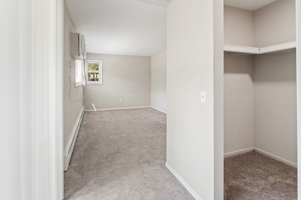 A room with a window and a carpeted floor.