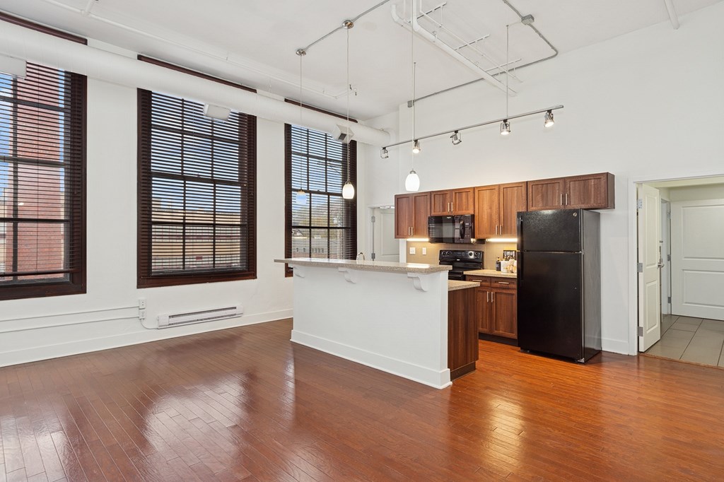 A kitchen with a black refrigerator and wooden cabinets.
