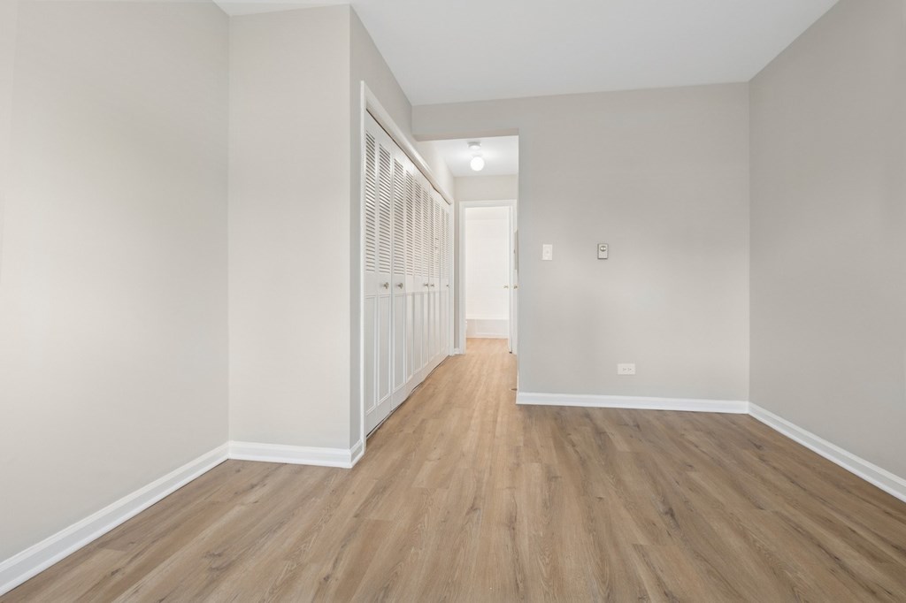A long hallway with wood floors and white walls.