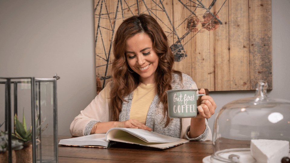 a woman sitting at a table with a book and a mug  at The Township at St. Charles, St. Charles, IL