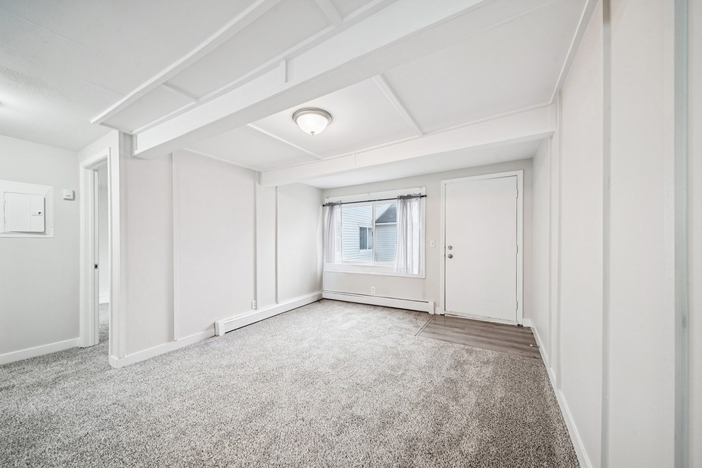 A spacious room with a carpeted floor and white walls.