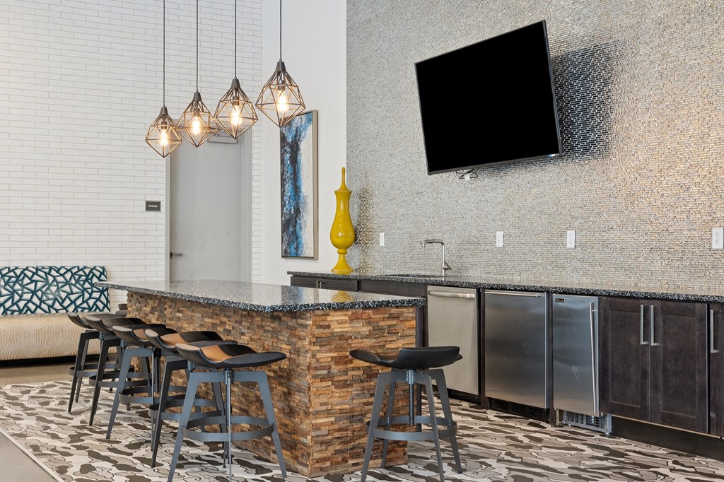 A modern bar area with a stone counter and stools.