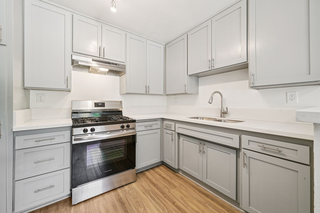A modern kitchen with white cabinets and a stainless steel stove.