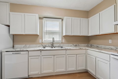 A kitchen with white cabinets and a marble countertop.