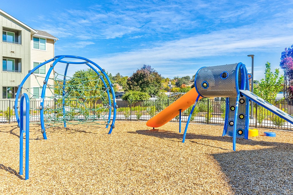A playground with a blue slide and a yellow slide.