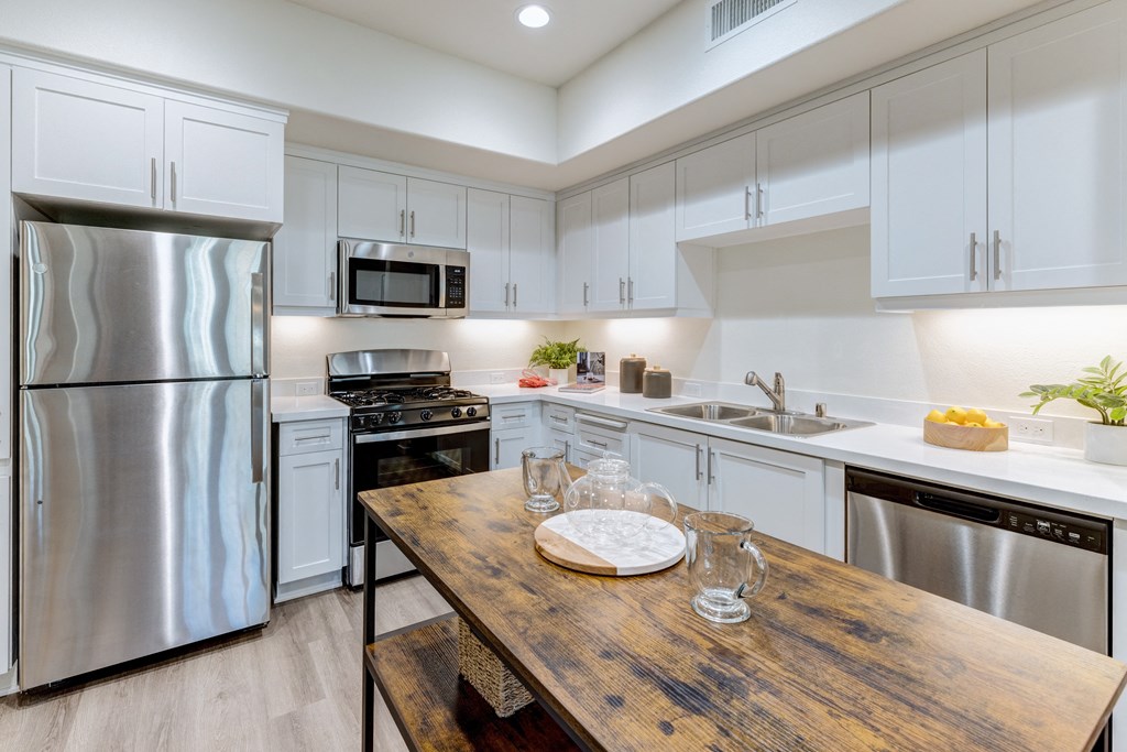 A kitchen with a wooden table and stainless steel appliances.