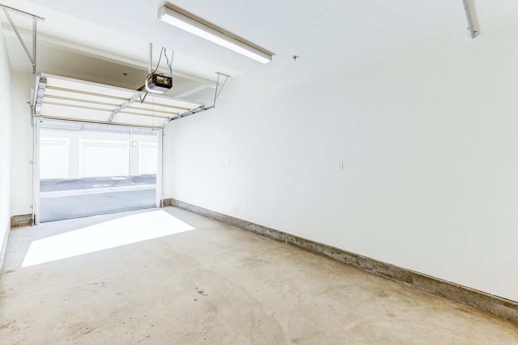 A large empty room with a window and a white wall.
