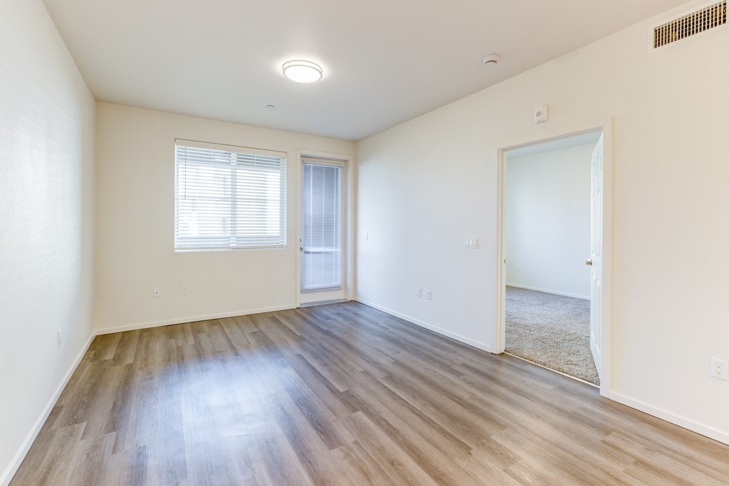 A room with wooden flooring and a window with blinds.