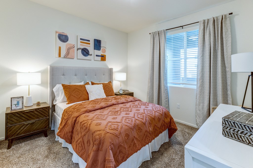 A bedroom with a bed, nightstand, and a painting on the wall.