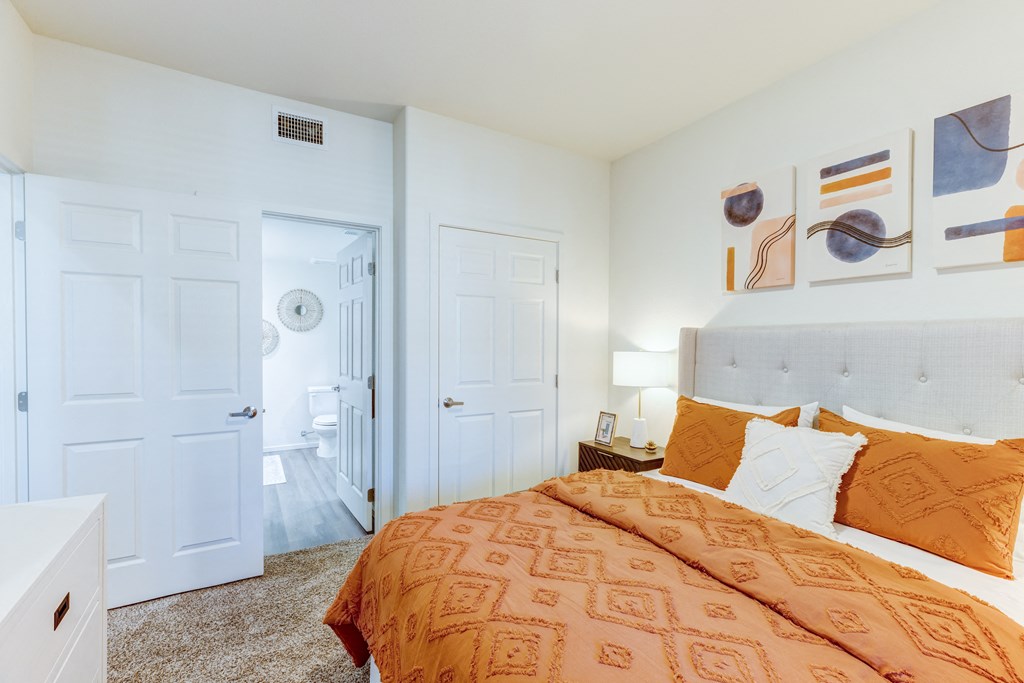 A bedroom with a bed, two doors, and a nightstand.