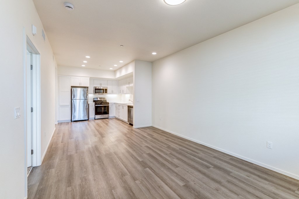 A spacious room with wooden flooring and white walls.
