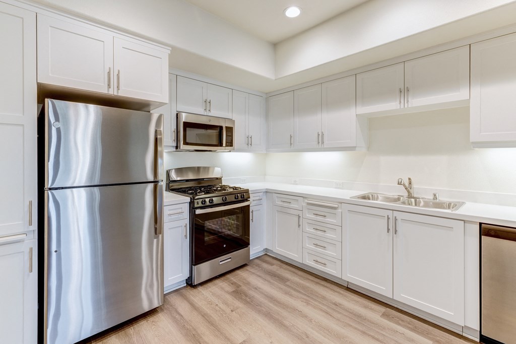 A modern kitchen with white cabinets and stainless steel appliances.