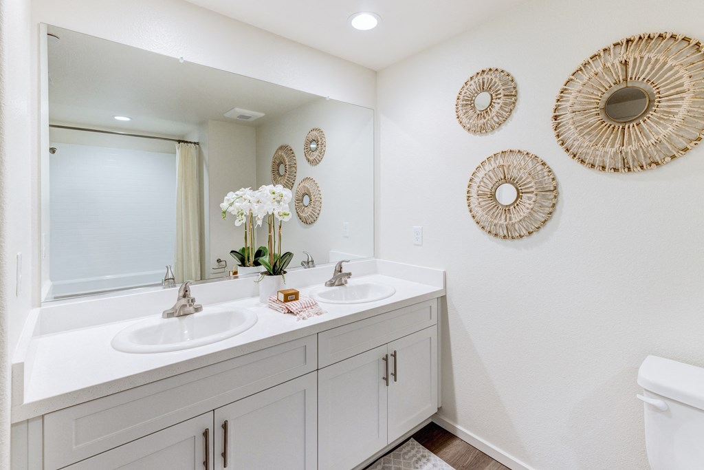 A white bathroom with two sinks and a toilet.