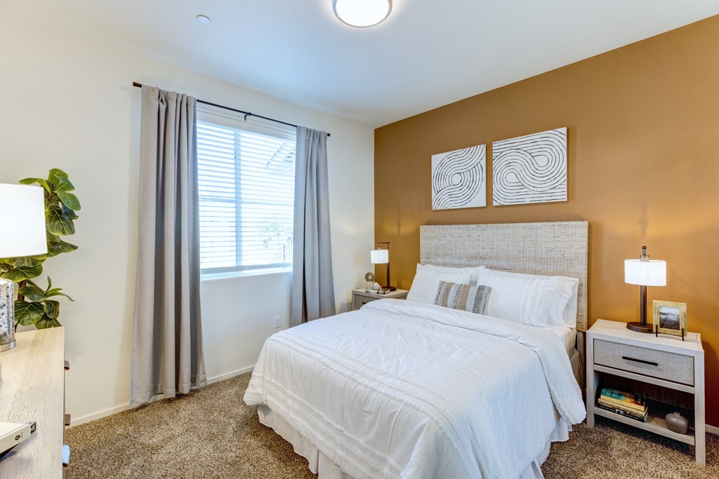 A bedroom with a large bed and a window with curtains.