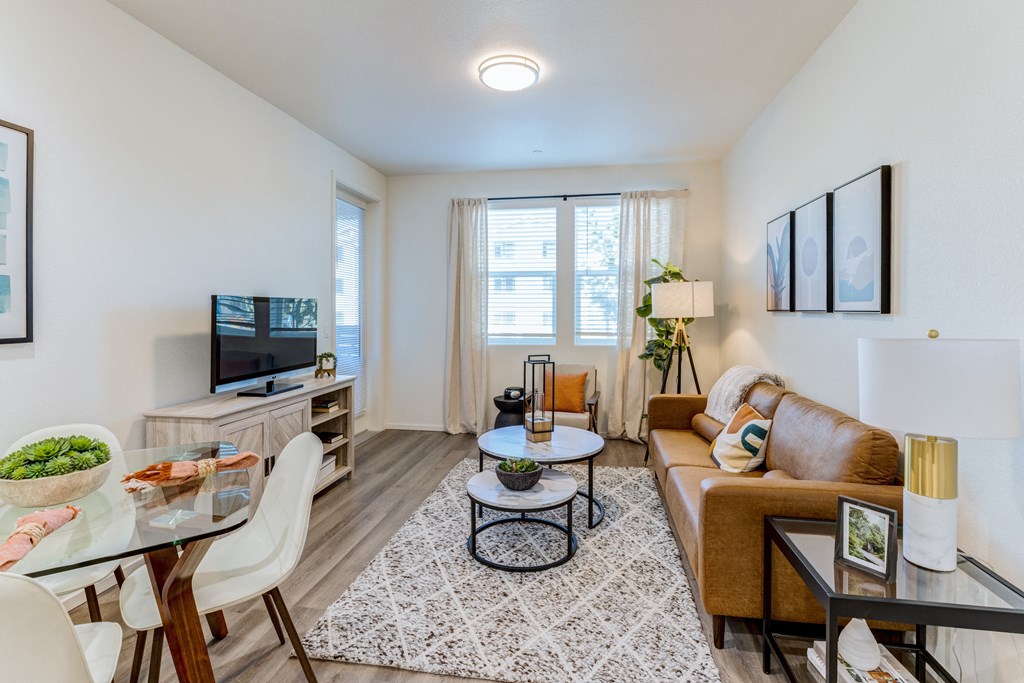 A living room with a brown couch, a glass table, and a television.