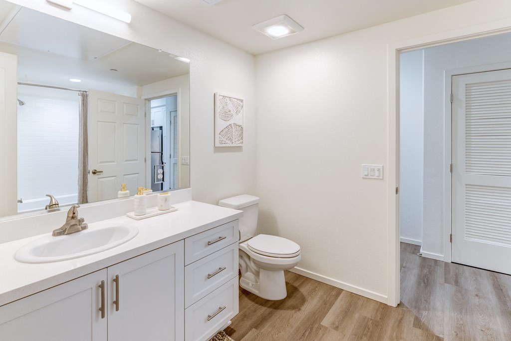 A white bathroom with a toilet, sink, and mirror.