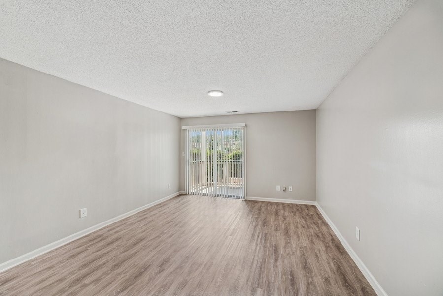 A room with wooden flooring and a sliding glass door.