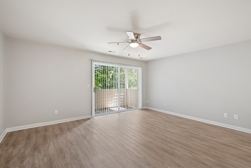 A room with a ceiling fan and sliding glass doors.