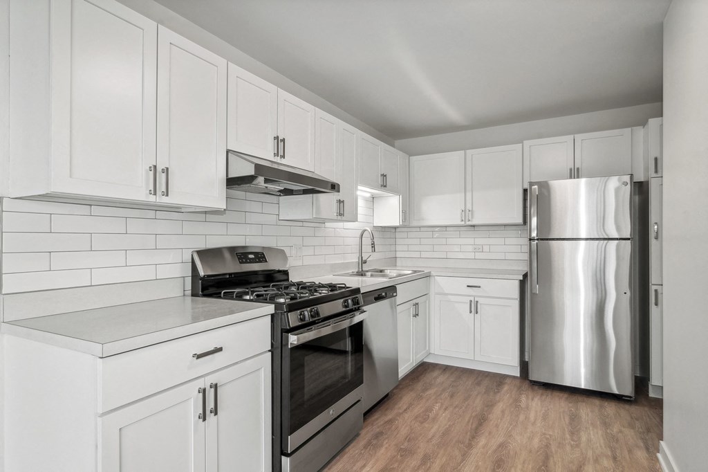 an all white kitchen with stainless steel appliances and white cabinets at The Reserve on Washington, Illinois