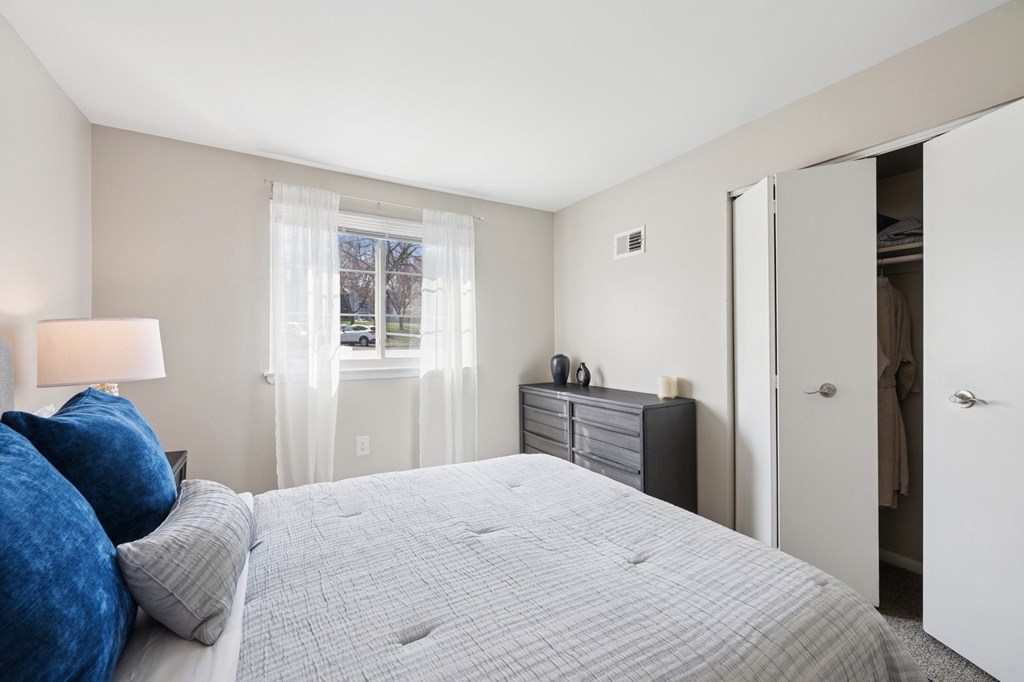 A bedroom with a large bed and a window with curtains.