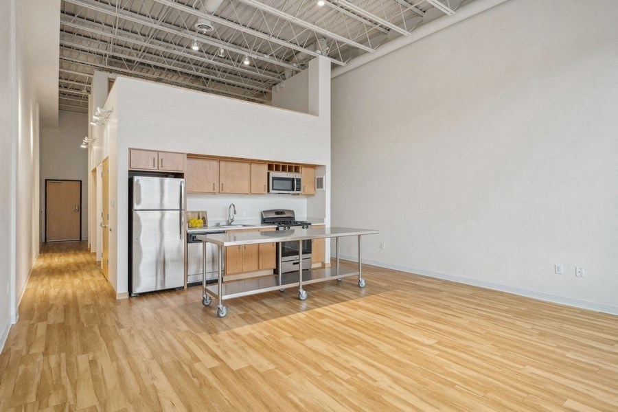 A kitchen area with a table and chairs in a room with wooden flooring.