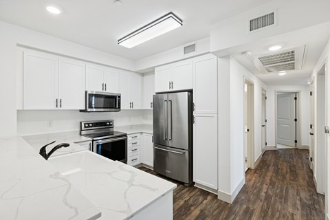 A kitchen with a white counter top and a refrigerator.