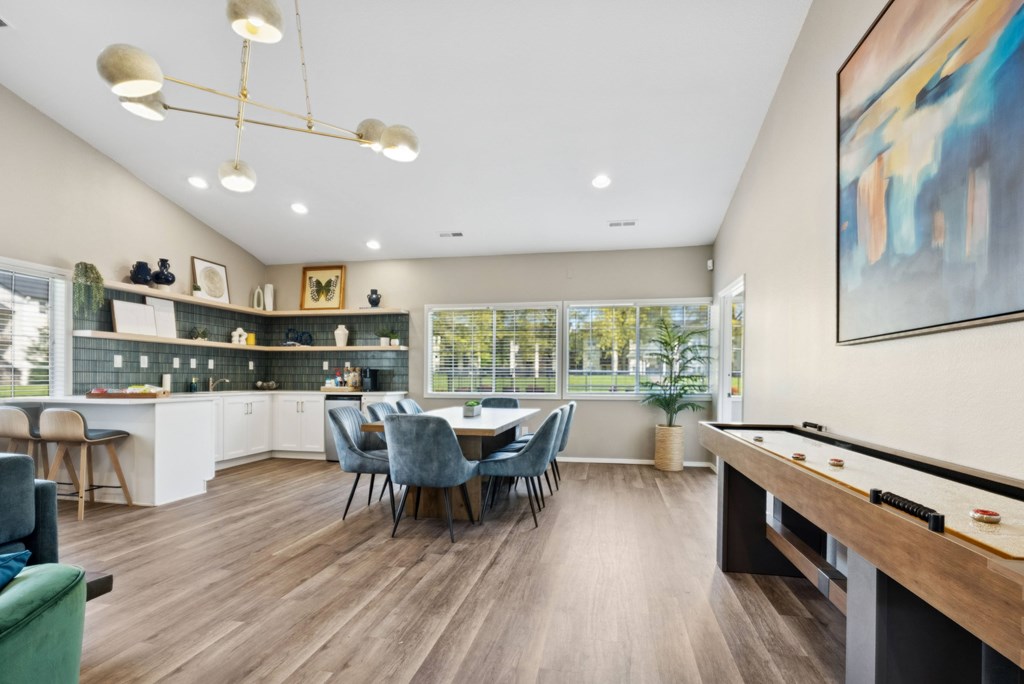 A well-lit room with a pool table and a dining table with chairs.
