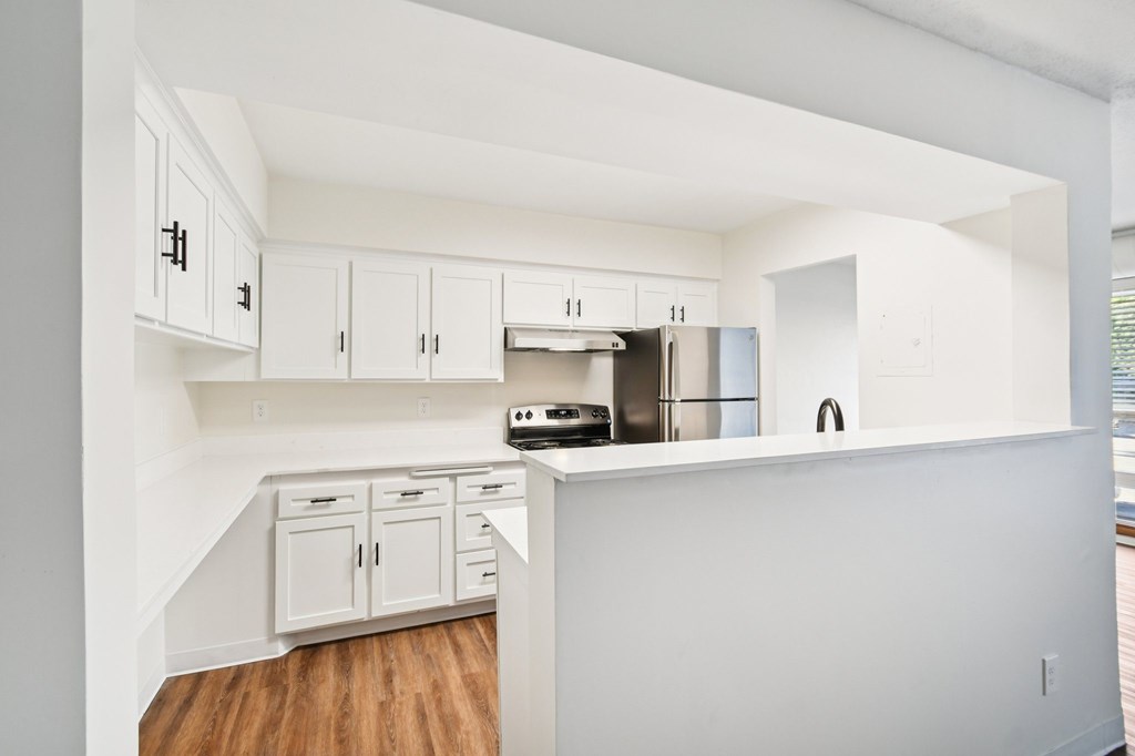 A kitchen with white cabinets and a wooden floor.