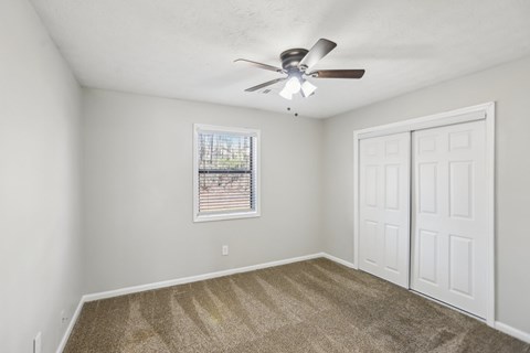 A room with a ceiling fan and carpeted floor.