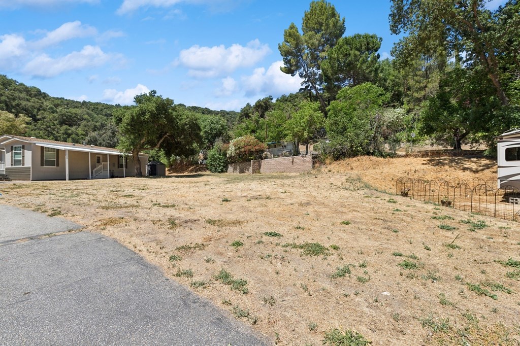 A house is surrounded by a fence and trees in a grassy area.