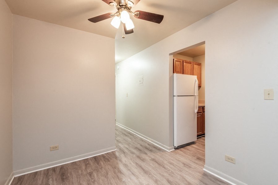 A white refrigerator in a kitchen with a ceiling fan.