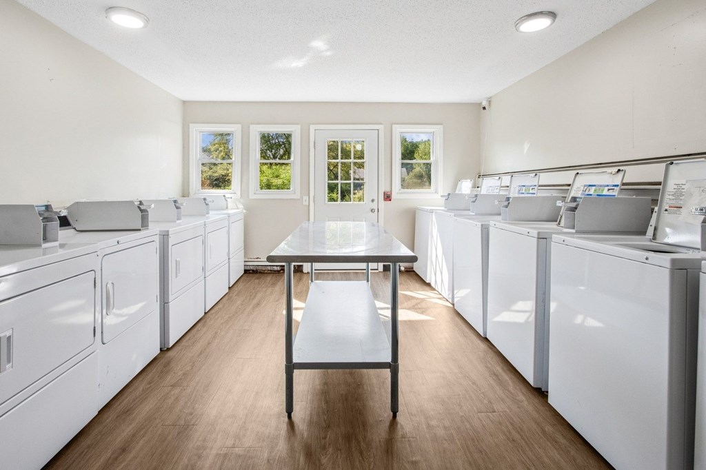A kitchen with white appliances and a table in the middle.