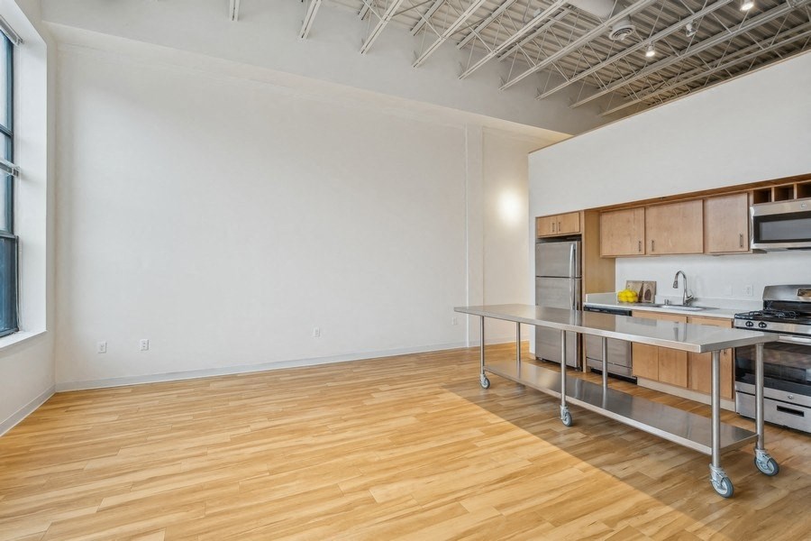 A kitchen area with a wooden floor and a white wall.