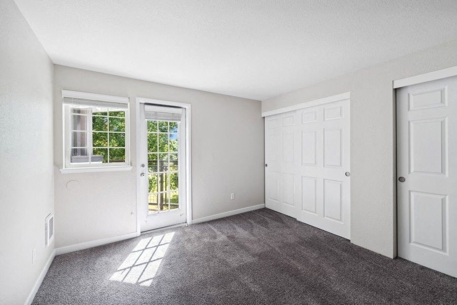 an empty living room with white walls and doors and carpet at Sundial Apartments, Wilsonvile, Oregon