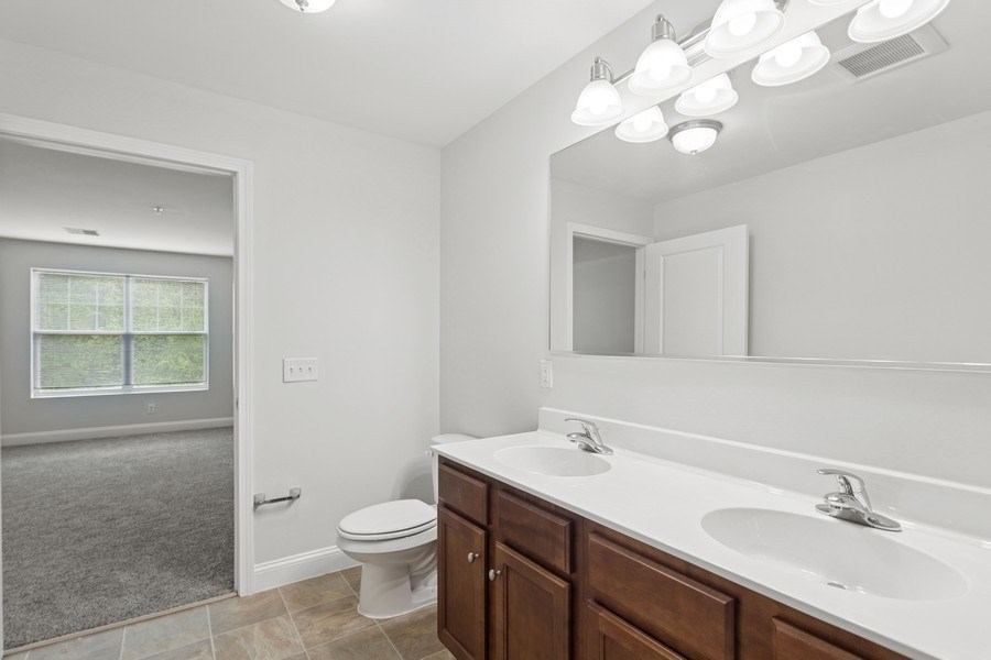 A bathroom with a toilet, sink, and mirror.