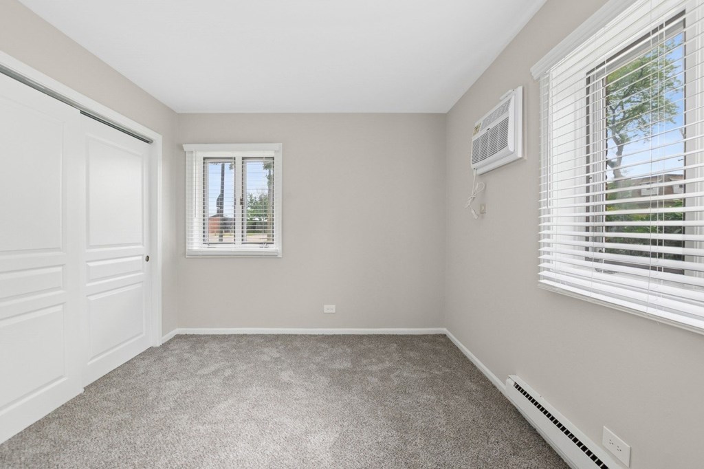 A bedroom with a window and a door.
