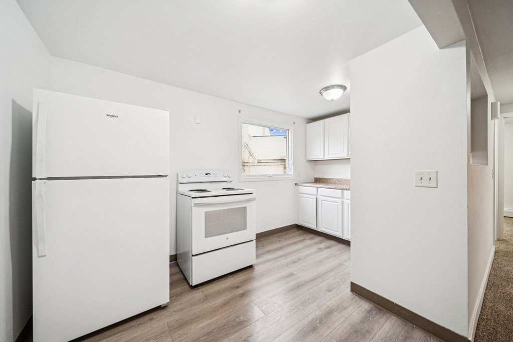 A white kitchen with a refrigerator, oven, and microwave.
