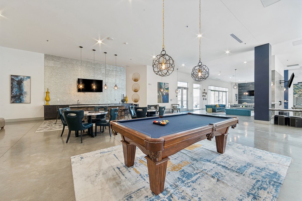 A pool table is in the middle of a room with a blue rug.