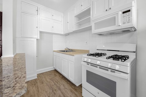 A white kitchen with a stove, microwave, and cabinets at Pleasant Oak Apartments, Oak Park, Illinois
