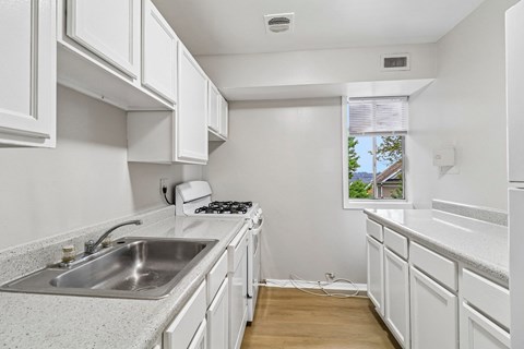 A kitchen with white cabinets and a stainless steel sink.