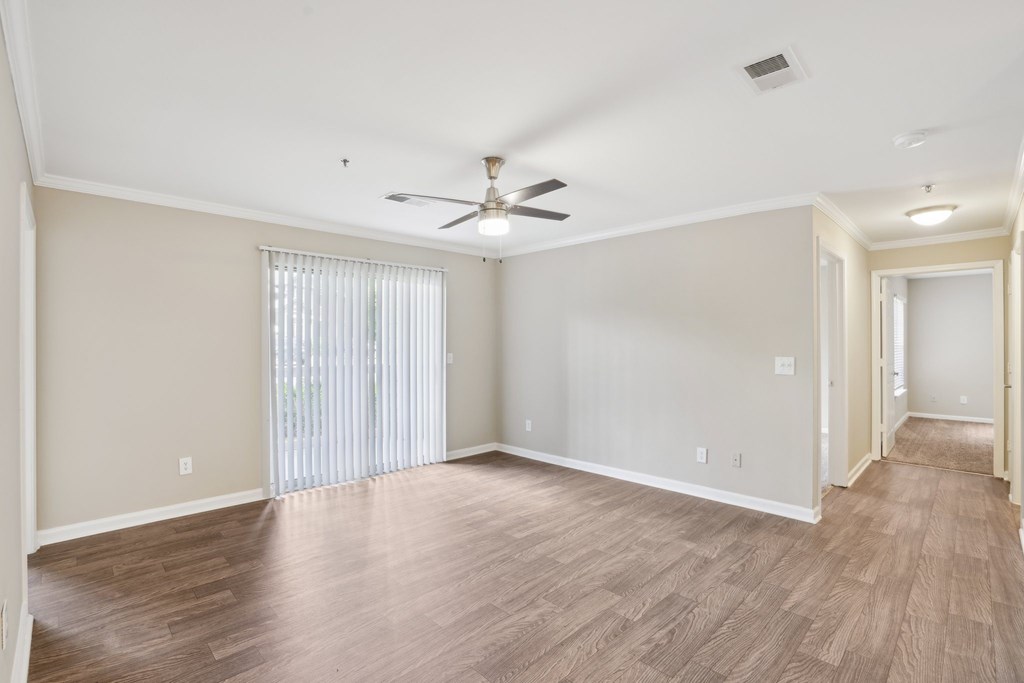 A living room with a ceiling fan and sliding glass doors.