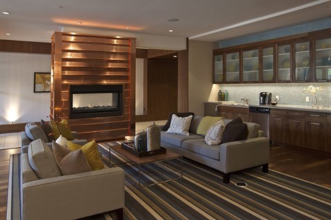 A modern living room with a fireplace and a striped rug.