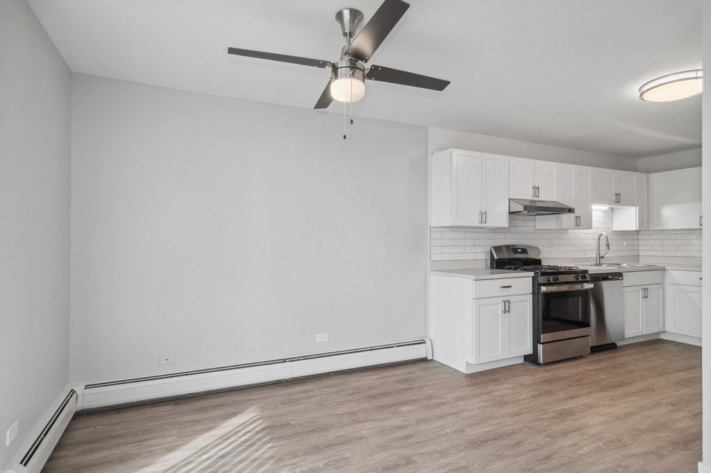 an empty living room with a ceiling fan and a kitchen at The Reserve on Washington, Naperville, 60565