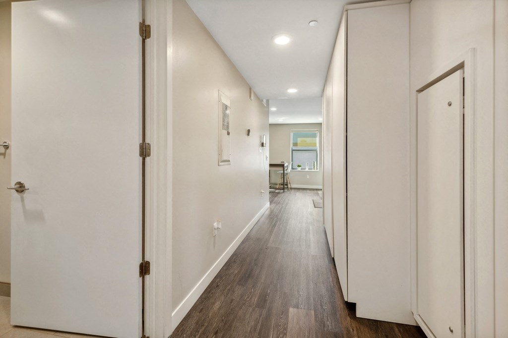 a hallway with white walls and wooden floors and white doors at The Rowe, Grand Rapids