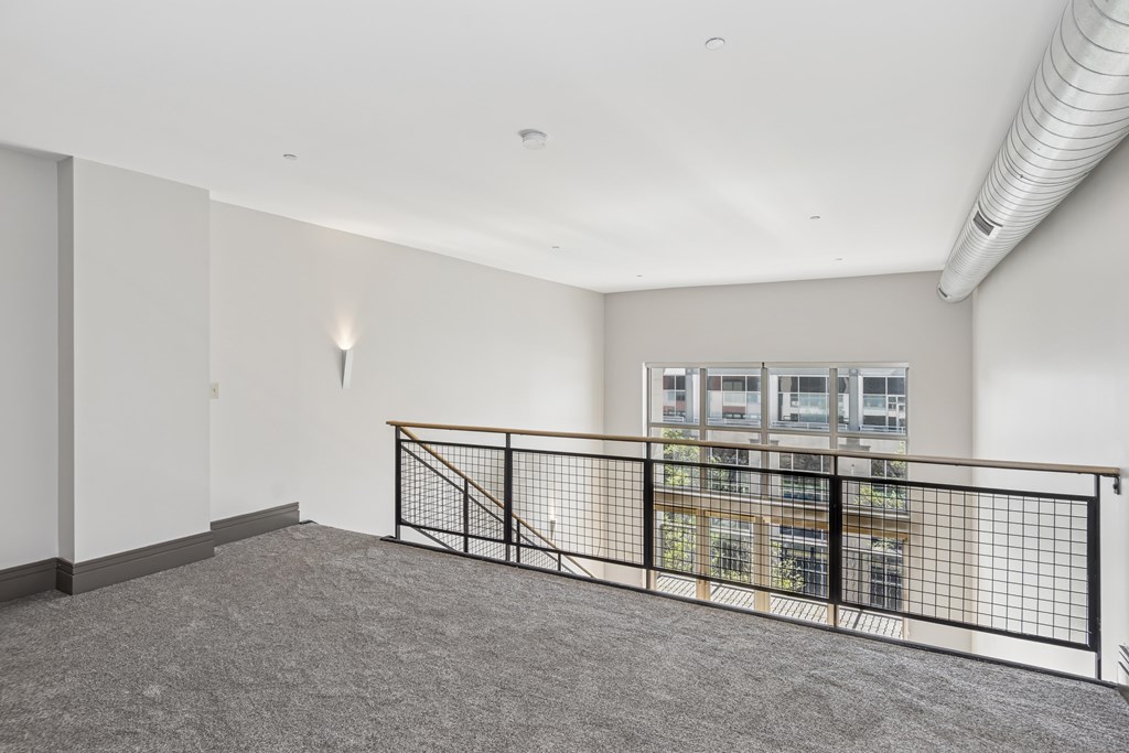 A room with a grey carpet and a black railing.