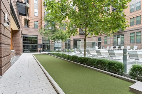 a courtyard with grass and chairs in front of a building