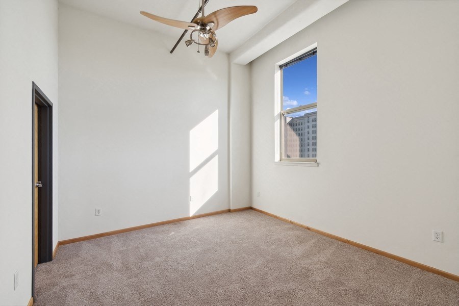 an empty bedroom with a ceiling fan and a window