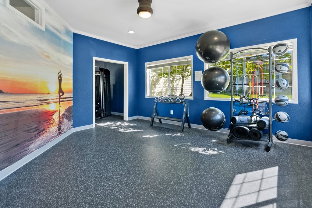 A room with a blue wall and a picture of a sunset on the wall.