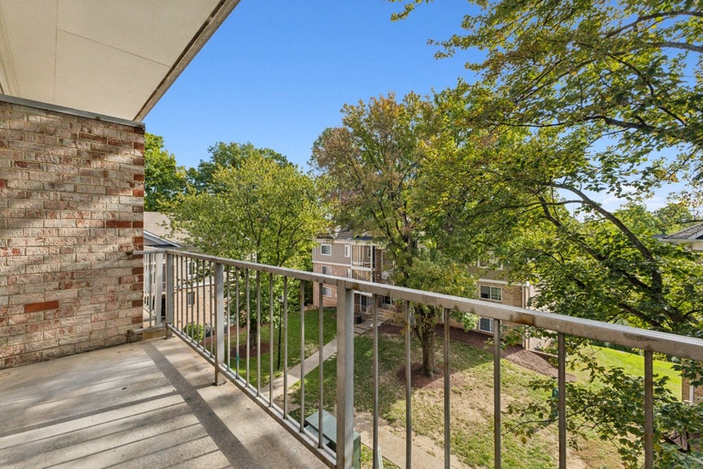 a balcony with a wooden railing and trees and a brick building at Briarwood Apartments, Dumfries, Virginia